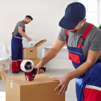 Profesyonel nakliyat elemanı koli bant makinesiyle taşıma kutusunu mühürlüyor.