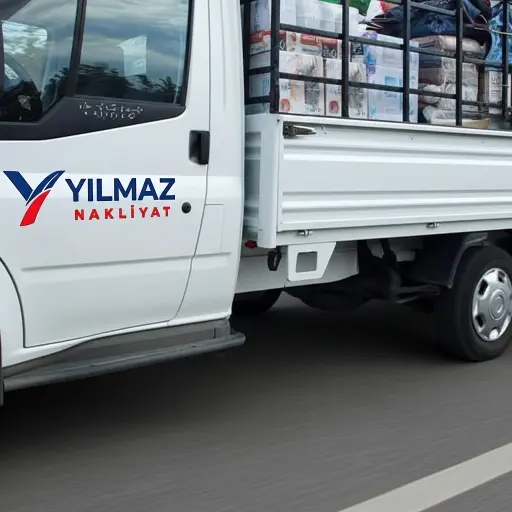 Yılmaz Nakliyat Yılmaz Nakliyat logolu, kasasında yük bulunan beyaz nakliye kamyoneti yolda ilerliyor.