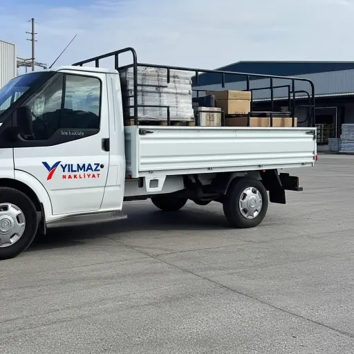 Beyaz Yılmaz Nakliyat kamyoneti, paletler ve kutular yüklü, depolama alanında nakliye hizmeti.